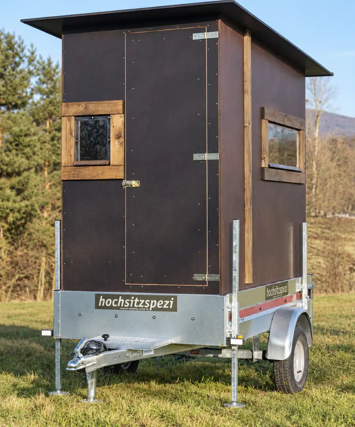 Kanzel Caravan: mobile Jagdkanzel von Holzbau Lins auf verzinktem Anhänger mit Stützen und Gitterrost auf einer Wiese