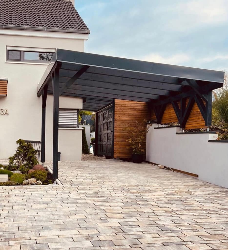 Carport mit anthrazitfarbener Holzkonstruktion und Flachdach an einem Wohnhaus, gebaut von Holzbau Lins