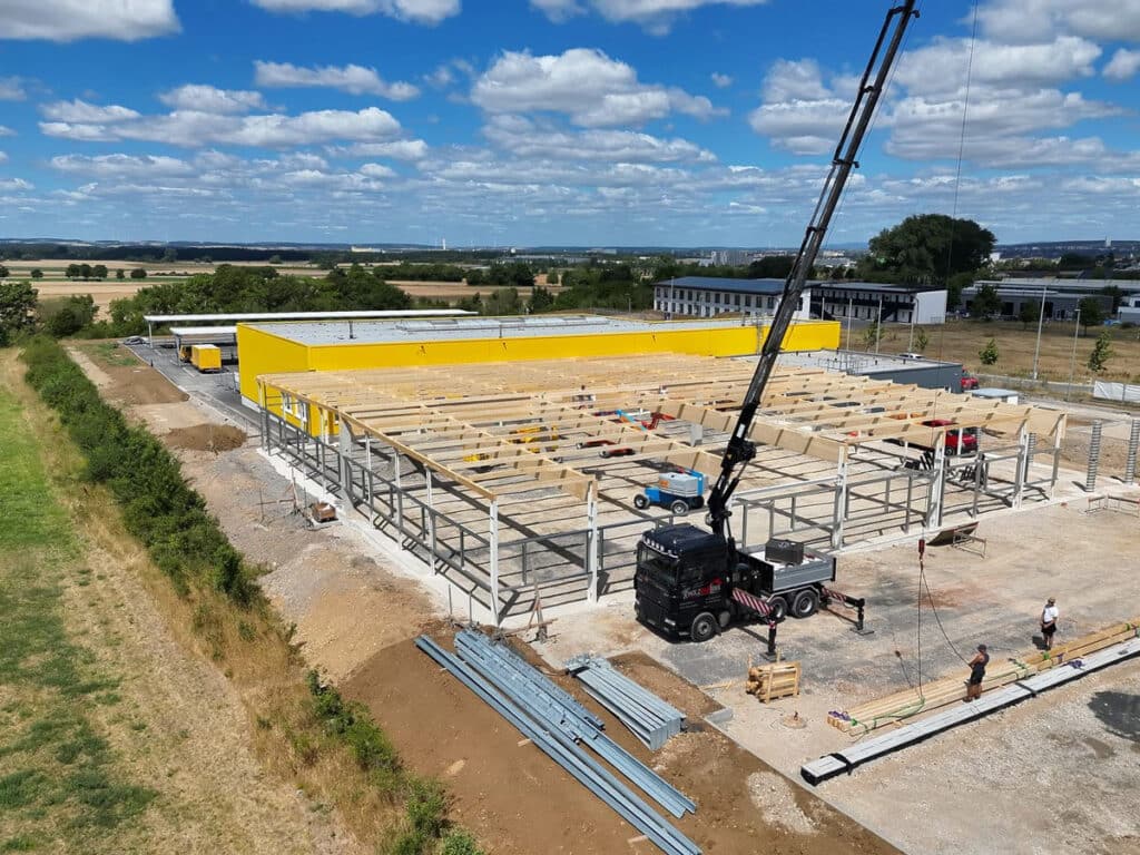 Dachkonstruktion aus Holz für ein Logistikzentrum, Montage mit Kran auf der Baustelle